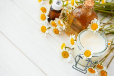 Papatya çiçekleri ve kozmetik şişeleri esaslı yağ ve beyaz ahşap arka planda özüt. Düz yatıyordu. Üst Manzara. Boşluğu kopyala