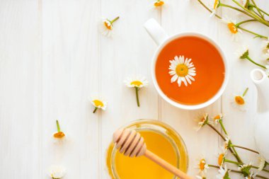 Taze papatya çiçekli bitki çayı ve beyaz ahşap arka planda bal. Yumuşak odak