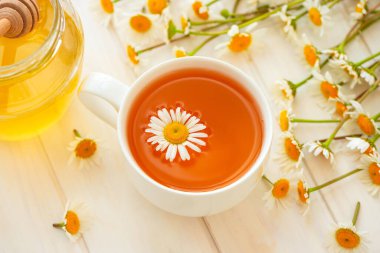 Taze papatya çiçekli bitki çayı ve beyaz ahşap arka planda bal. Yumuşak odak