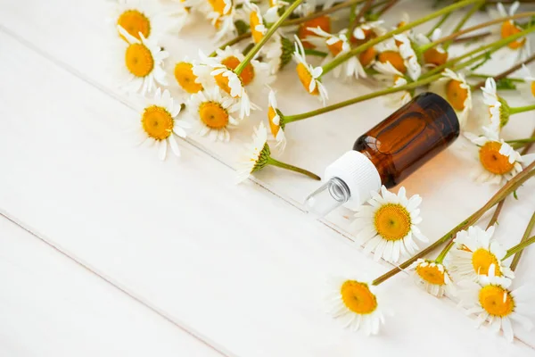 Kamille Bloemen Cosmetische Flessen Etherische Olie Witte Houten Ondergrond Plat — Stockfoto