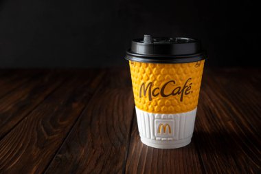 McDonald 's restoranı. Koyu ahşap arka planda McCafe kağıt kahve fincanı. Lviv, Ukrayna - 18 Haziran 2020