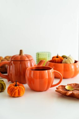 Balkabağı süslemeli sonbahar çay seti ve beyaz bir masada pasta..