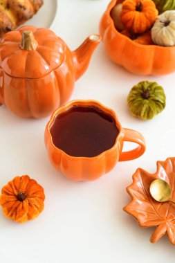 Balkabağı süslemeli sonbahar çay seti ve beyaz bir masada pasta..