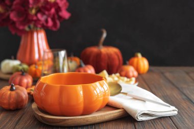 Kremalı balkabağı çorbası. Koyu ahşap masada kabak şeklinde bir kasede servis ediliyor..