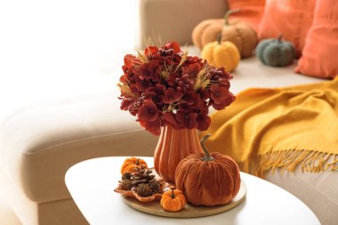 Sehpası, balkabağı ve çiçek aranjmanı olan Şükran Günü oturma odası dekoru..