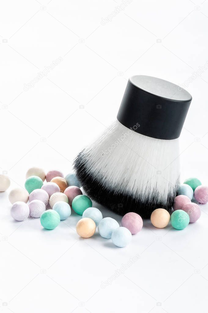 Mineral powder pearls and kabuki makeup brush vertical view.