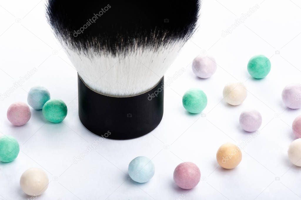 Mineral powder pearls and kabuki makeup brush close up view.