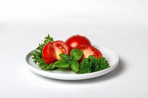 Fresh tomatoes with basil and parsley on plate, white background