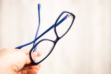Elinde mavi çerçevede gözlük (gözlük)
