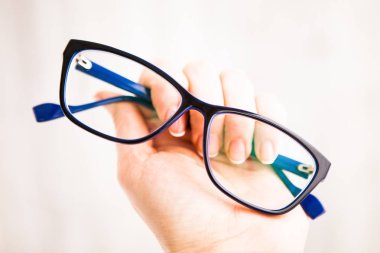 Elinde mavi çerçevede gözlük (gözlük)