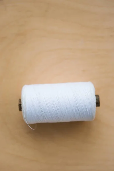 木製の背景に白い機械の糸を持つボビン — ストック写真