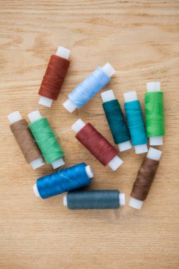 Ahşap arkaplanda farklı renkte iplikler dikiliyor