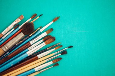 Turquois arka plan üzerinde boya fırçaları kümesi