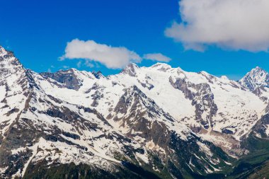 Karlı dağlar. Dağların ve mavi gökyüzünün güzel manzarası