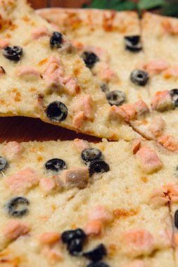 Restorandaki ahşap masada zeytinli pizza.