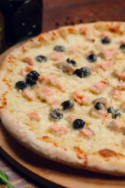 Restorandaki ahşap masada zeytinli pizza.