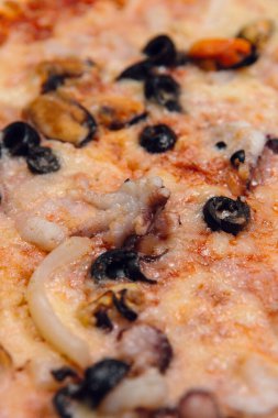 Bir restoranda ahşap masada deniz ürünleri pizzası.