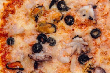 Bir restoranda ahşap masada deniz ürünleri pizzası.