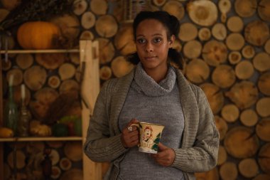 Bir fincan sıcak bir içecek olan kırsal sade ortamda koyu tenli kız