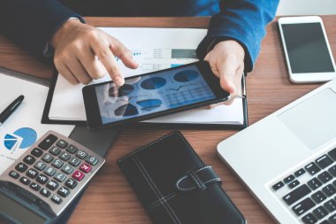İşadamı metin bilgileri kullanarak dijital tablet üzerinde mali istatistiksel grafik verileri çözümlemek ve yatırım proje maliyetini hesaplamak için eller.