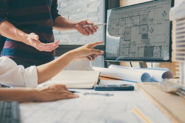 Görüntü mühendis veya mimar ortak mimari projesi ile çalışma, çizim ve muayene mimari proje planı, çalışma alanı üzerinde çizim için Toplantı.