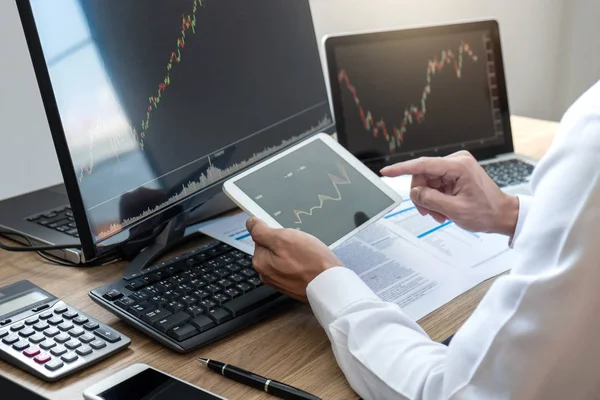 Borsa konsepti, borsa simsarı ekran ekranı ile çalışan ve analiz eden borsacı, sunulan verilere işaret ediyor ve bir borsada anlaşma yapıyor, iş adamı çevrimiçi hisse senedi ticareti yapıyor.