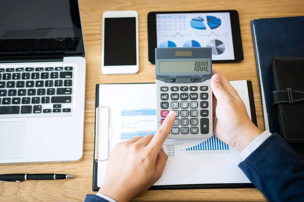 Businessman hands using text information on digital tablet to analyze financial statistical chart data and calculate cost of investment project.