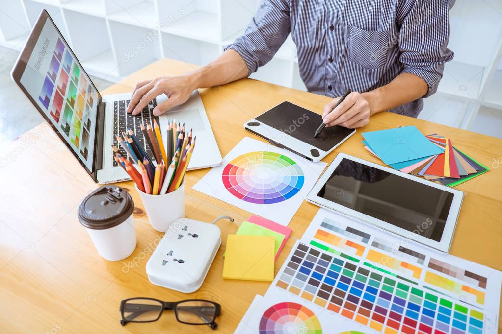 Young creative graphic designer working on project architectural drawing and color swatches, selection coloring on graphic chart with work tools and equipment.