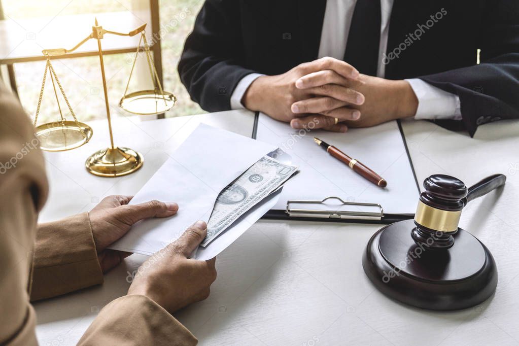 Business woman giving bribe money the form of dollar bills to mature counselor while give success the deal to finishing contract agreement, Bribery and corruption concept.