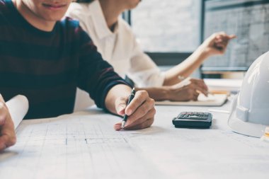 Mimar veya inşaat mühendislik ekibi planı denetim işyerinde, çizim ve toplantı için ortak çalışma mimari proje çizimi üzerinde çalışmaya eller.