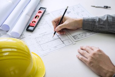 İnşaat mühendisliği veya mimar elleri işyerlerinde ayrıntılı teftiş üzerinde çalışırken, mimarlık projesi için bilgi çizimi ve çizimlerini kontrol ederler.
