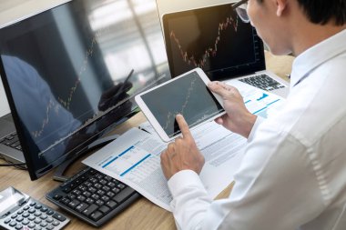 Borsa konsepti, borsa simsarı ekran ekranı ile çalışan ve analiz eden borsacı, sunulan verilere işaret ediyor ve bir borsada anlaşma yapıyor, iş adamı çevrimiçi hisse senedi ticareti yapıyor.