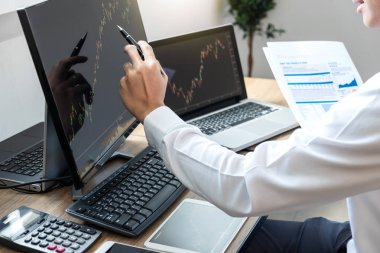 Borsa konsepti, borsa simsarı ekran ekranı ile çalışan ve analiz eden borsacı, sunulan verilere işaret ediyor ve bir borsada anlaşma yapıyor, iş adamı çevrimiçi hisse senedi ticareti yapıyor.