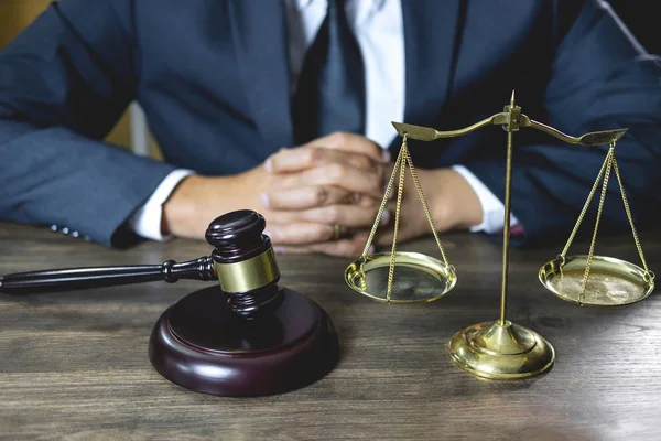 Legal law, advice and justice concept, male lawyer or notary working on a documents and report of the important case and wooden gavel, balance on table in courtroom.