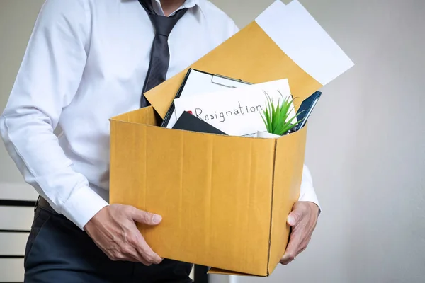 Businessman sending letter will being resignation and carrying packing belongings company and files into brown cardboard box, changing and resigning from work concept.