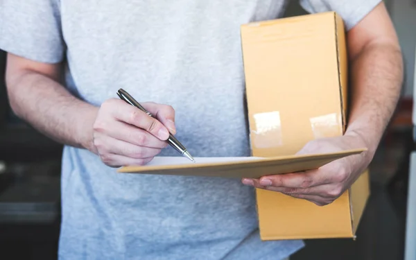 Delivery mail man giving parcel box to recipient and signature form, Young owner signing receipt of delivery package from post shipment courier, Home delivery service and working with service mind.