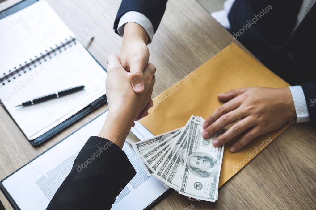 Dishonest cheating in business illegal money, Businessman handshake money of dollar bills in hands from while give success the deal, Bribery and corruption concept.