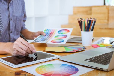 Genç yaratıcı grafik tasarımcı çalışma proje mimari çizim ve renk örnekleri, iş araçları ve ekipmanları ile grafik grafik üzerinde boyama seçimi hakkında.