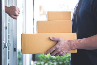 Ev sahibi açık kapı açık havada, ellerde koli ile ev teslim servisi ayakta ve hizmet zihin ile çalışan teslimatçı için.