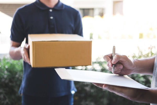 Delivery mail man giving parcel box to recipient, Young man signing receipt of delivery package from post shipment courier at home.