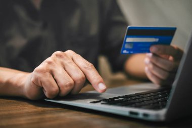 Kredi kartı tutan ve laptop için online yazarak işadamı 