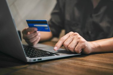 Kredi kartı tutan ve laptop için online yazarak işadamı 