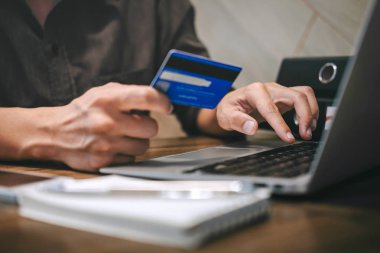 Kredi kartı tutan ve laptop için online yazarak işadamı 