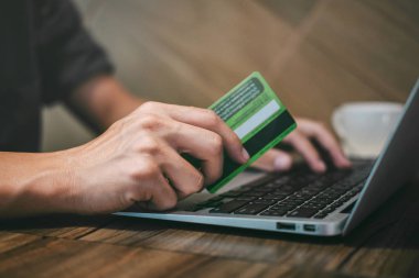 Kredi kartı tutan ve laptop için online yazarak işadamı 