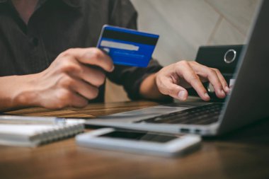 Kredi kartı tutan ve laptop için online yazarak işadamı 