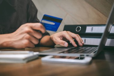 Kredi kartı tutan ve laptop için online yazarak işadamı 