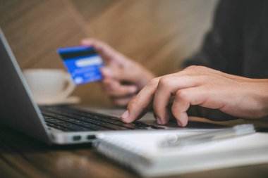 Kredi kartı tutan ve laptop için online yazarak işadamı 