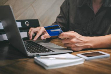 Kredi kartı tutan ve laptop için online yazarak işadamı 