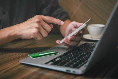 Kredi kartı tutan ve dizüstü f smartphone kullanarak iş adamı