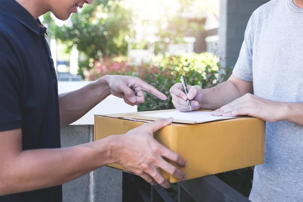Entrega homem de correio dando caixa de pacote para o destinatário, sinal de jovem — Fotografia de Stock